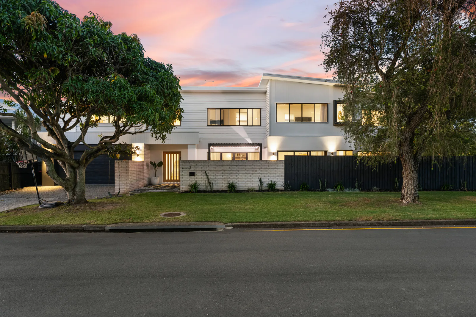 Twilight exterior of a Brisbane home framed by mature trees
