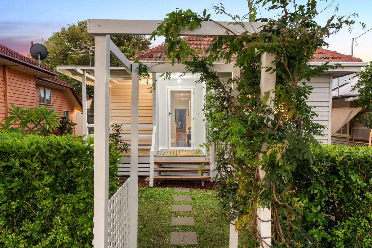 Character home exterior framed by a garden path and white pergola