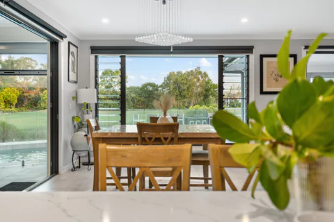 Dining area opening to a pool and garden in Banksia Beach