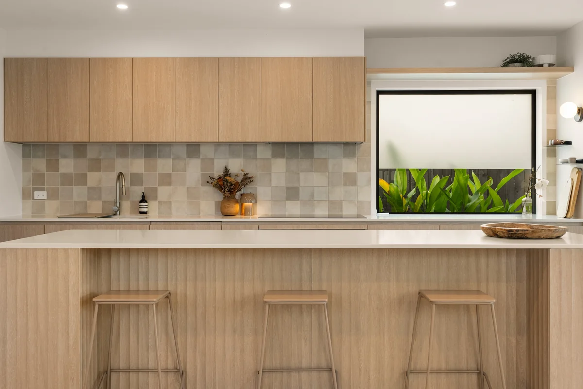 Warm timber kitchen with tiled splashback, island bench and garden-facing window