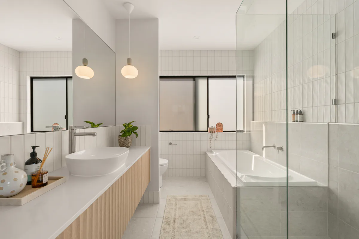 White-tiled bathroom with a timber vanity and bath in Brighton